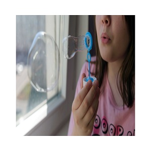 White girl with brown hair and freckles using a bubble wand to blow bubbles