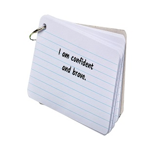 Stack of index cards with the words I am confident and brave written on the top card.