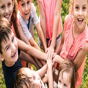 Seven children standing in a circle with their hands criss crossed in the middle of the circle.