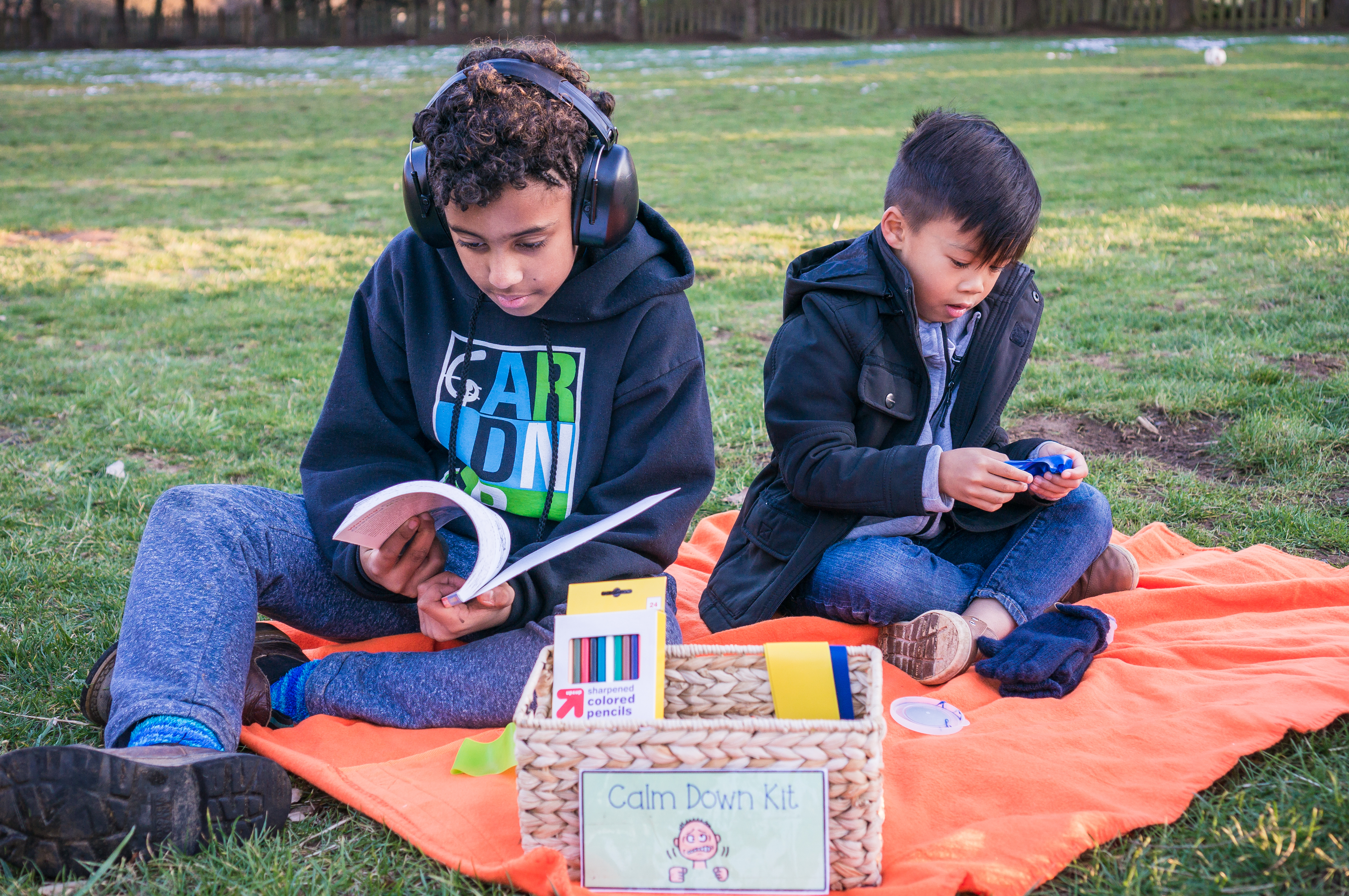 Two elementary students sitting on a blanket surrounded by calming items.